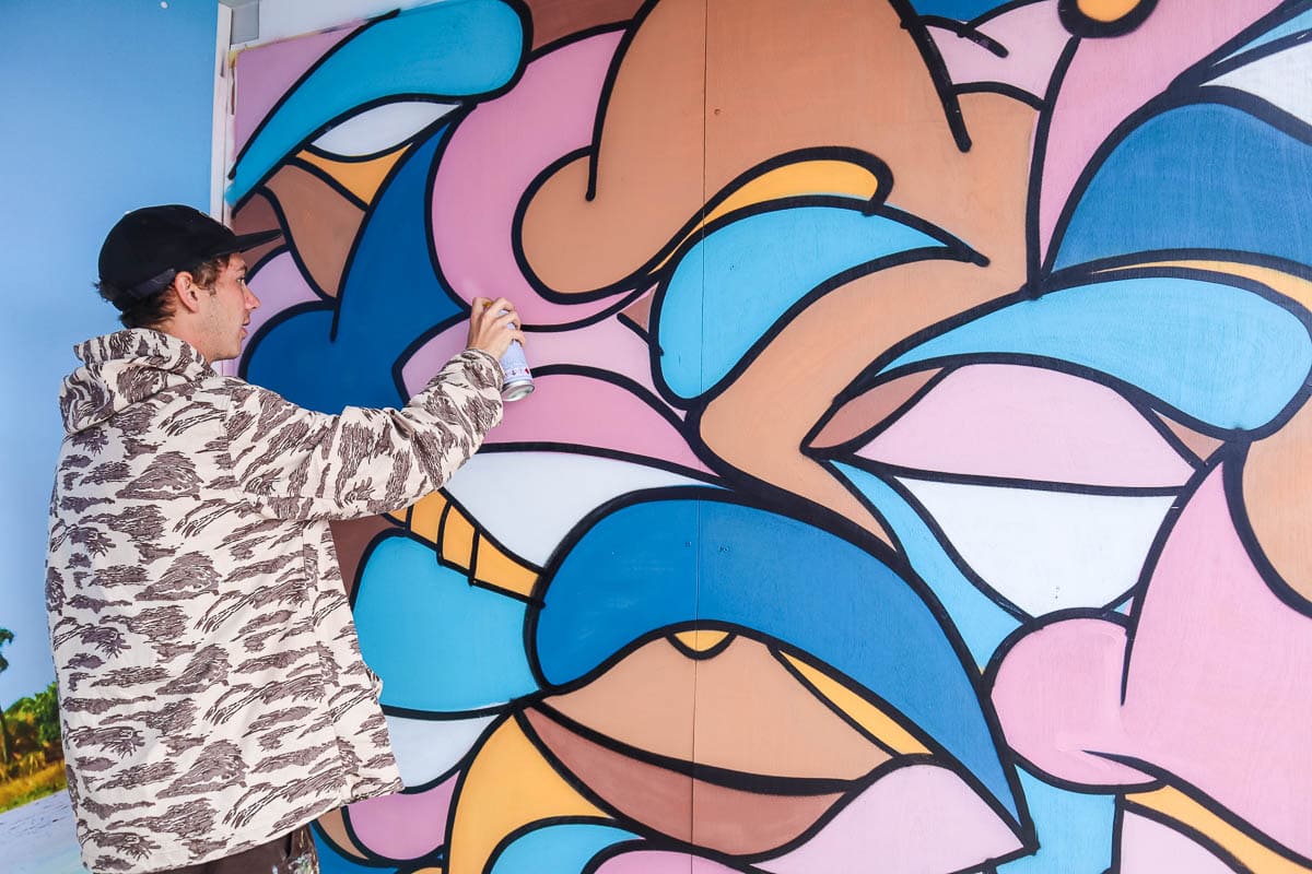 @slakarts creating a mural at the Visit St. Pete/Clearwater stand at Boardmasters 2018
